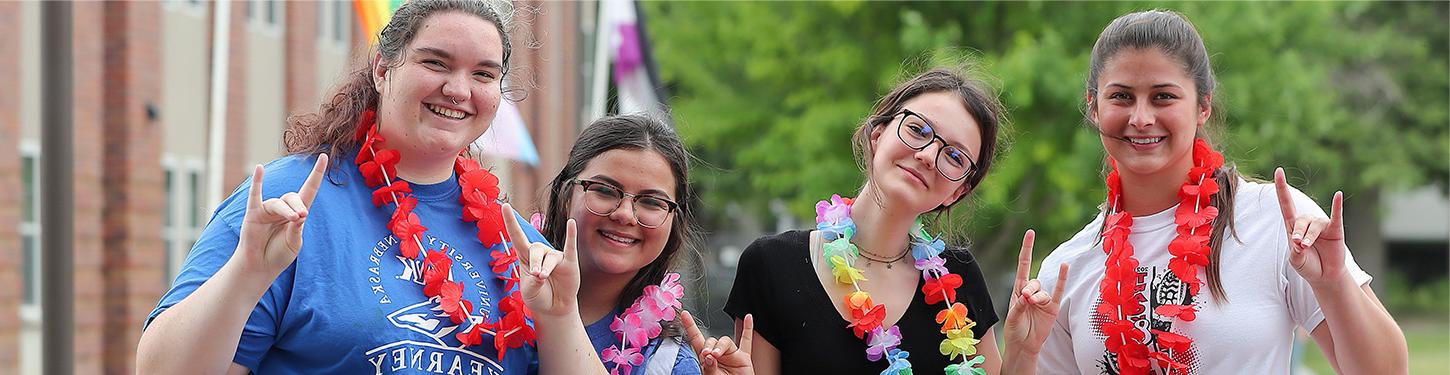 Four students pose for a picture at a pride month event